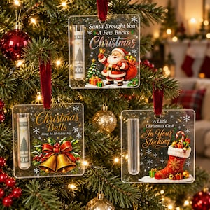 May include: Three square clear acrylic Christmas ornaments with red velvet ribbons. Each features a test tube for cash, festive graphics, and text: Santa Brought You A Few Bucks Christmas, Christmas Bells Ring In Holiday Joy, and A Little Christmas Cash In Your Stocking.
