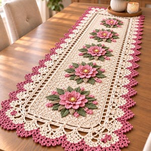 May include: A rectangular crochet table runner featuring a cream-colored base with a scalloped border in dark pink. The runner is decorated with five evenly spaced, three-dimensional pink flower appliqués with green leaves and yellow centers.