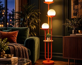 May include: A tall orange floor lamp featuring three stacked white spherical glass globes, each resting on a circular orange tray. The lamp includes a small wooden shelf holding a potted plant and stands on a round orange base.