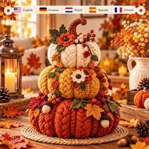 May include: A stacked three-tier crochet pumpkin decoration featuring a cream top, yellow middle, and orange bottom pumpkin. Each pumpkin has a braided texture and is adorned with crocheted autumn leaves, flowers, berries, and acorns.