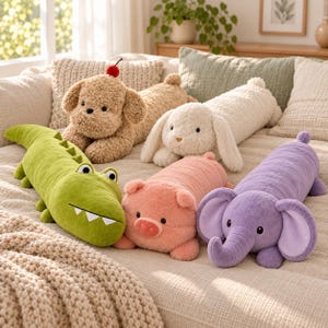 May include: A collection of five plush animal pillows including a tan dog with a red cherry on its head, a white rabbit, a green alligator with white teeth, a pink pig, and a purple elephant, all featuring soft, textured fabric and embroidered eyes.