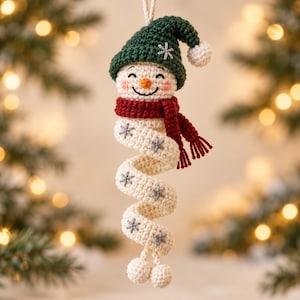 May include: A crocheted snowman ornament with a spiral body, wearing a dark green hat with a white pom-pom and a red scarf. The off-white body features embroidered grey snowflake patterns and ends with two small white pom-poms at the base.