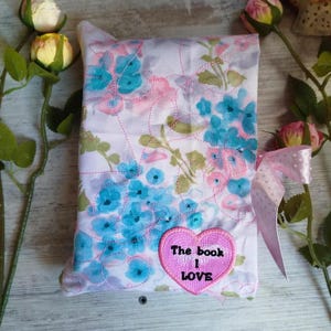 May include: A pink floral fabric book cover with a pink heart-shaped patch that says "The book I love".