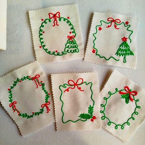 May include: A collection of six small, square fabric patches with embroidered Christmas designs. Each patch features a white background with green wreaths, Christmas trees, and red bows. The embroidery is detailed and festive.