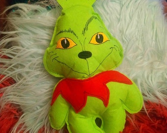 May include: Green felt plush toy of the Grinch from the book "How the Grinch Stole Christmas". The Grinch has a red felt collar and a mischievous grin.