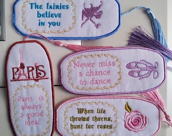 以下が含まれることがあります： インスピレーションを与える引用句とデザインが刺繍されたブックマーク。妖精と「The fairies believe in you」というテキストが特徴です。もう一つは「Paris is always a good idea」と書かれています。その他、「Never miss a chance to dance」と「When life throws thorns, hunt for roses」と書かれています。