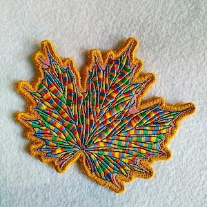 Könnte beinhalten: Gestickter Ahornblatt-Aufnäher mit einem lebendigen, mehrfarbigen Design. Das Blatt zeigt einen Regenbogen aus Farben, darunter Rot, Gelb, Blau und Grün, mit einem goldenen Rand. Ideal zum Verzieren von Kleidung oder Accessoires.