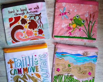 Può includere: Quattro pochette con cerniera ricamate con diversi disegni. La prima pochette è rosa con una rana verde e una libellula. La seconda pochette è bianca con una scena di montagna e il testo "Faith can move mountains". La terza pochette è bianca con una scena di spiaggia e il testo "Sun-kissed nose". La quarta pochette è rosa con una scena autunnale e il testo "Hand in hand we walk through Autumn."
