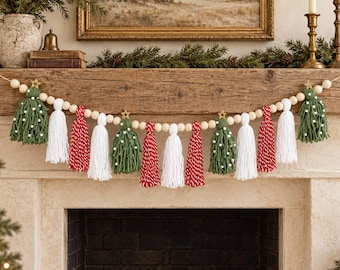 May include: A decorative garland featuring natural wooden beads strung together with alternating yarn tassels in green, white, and red. The green tassels are shaped like trees with small white dots and topped with tiny gold stars.