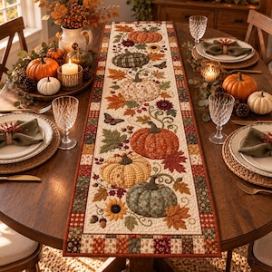 May include: A rectangular quilted table runner featuring a repeating pattern of pumpkins, autumn leaves, sunflowers, and butterflies in shades of orange, green, and brown, bordered by a patchwork design of small squares in coordinating autumn colours.