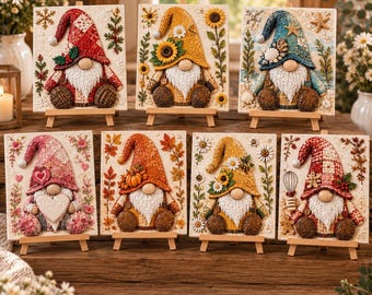 May include: Seven rectangular canvases on wooden easels, each featuring a textured gnome illustration. Designs include a red plaid winter gnome, a yellow sunflower gnome, a blue coastal gnome, a pink heart gnome, an orange autumn gnome, a yellow daisy gnome, and a red plaid baking gnome.