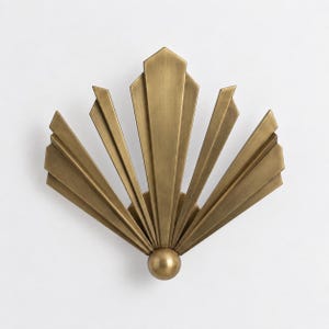 Könnte beinhalten: Eine Wandleuchte mit fächerförmigem Design und mehreren strahlenförmig angeordneten, messingfarbenen Metalllamellen. Die Struktur geht von einer zentralen, kugelförmigen, messingfarbenen Basis aus und erzeugt ein symmetrisches, geometrisches Sonnenstrahlen-Design.