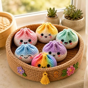 Op de afbeelding: Een ronde, beige gehaakte mand met een gele kwast en bloemaccenten, met daarin zes kleine, ronde gehaakte knuffels in de vorm van gestoomde broodjes. Elk broodje heeft een unieke pastelkleur, een lachend gezichtje en een geknoopt bovenstukje.