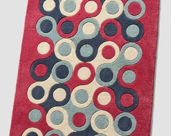 May include: A rectangular area rug featuring a vibrant red background with an interconnected pattern of circles in shades of navy blue, light blue, and cream. The design consists of linked circular shapes that create a continuous, flowing motif.