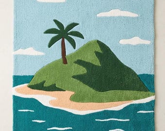 May include: A rectangular rug featuring a tufted landscape design of a green island with a single palm tree surrounded by teal ocean water. The sky is light blue with white clouds, and the island has a tan sandy beach. A small logo reads STR RUGS.