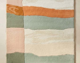 May include: A rectangular area rug featuring a color-blocked design with horizontal and vertical sections in shades of terracotta, sage green, cream, and soft pink. The rug has a textured pile surface and a small white label reading STR RUGS.