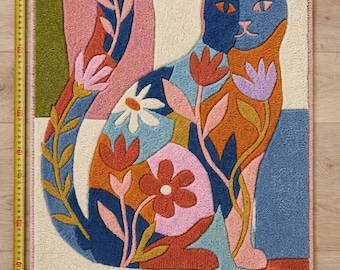 May include: A rectangular tufted rug featuring a cat with a floral pattern in shades of blue, orange, pink, and green. A yellow measuring tape along the left side and bottom shows the rug is approximately 33 inches tall and 22 inches wide.