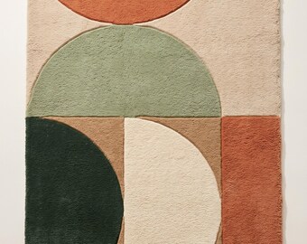 May include: A rectangular area rug featuring a tufted texture with a geometric pattern of semicircles and rectangles in shades of terracotta, sage green, dark forest green, beige, and tan, arranged in a balanced, layered composition.