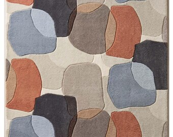 May include: A rectangular area rug featuring a repeating pattern of irregular, rounded shapes in shades of terracotta, slate blue, charcoal gray, and beige. The design consists of textured, raised sections separated by recessed lines.
