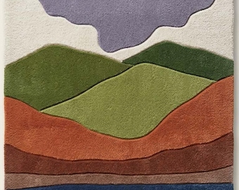 May include: A rectangular area rug featuring a layered landscape design with distinct color bands of purple, cream, light green, dark green, terracotta, brown, and blue. The rug has a textured pile surface and a small white logo tag reading STR RUGS.