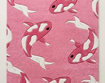 May include: A rectangular rug with a textured pink background featuring a repeating pattern of koi fish. Each fish is rendered in shades of pink and white with a small black eye. The design is consistent across the surface of the rug.