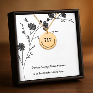 May include: A gold-colored necklace with a round pendant featuring the number 717. The pendant is inscribed with "My heart belongs to a state trooper." The necklace is displayed in a black box with floral artwork and the text "Behind every brave trooper is a heart that loves him."