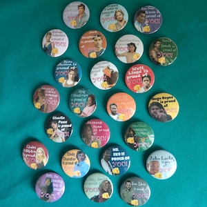 Op de afbeelding: Een verzameling van vierentwintig ronde buttons met diverse karakterportretten. Elke button toont de naam van een persoon gevolgd door de tekst is proud of YOU! en bevat een kleine gele afbeelding van een wijzende vinger.