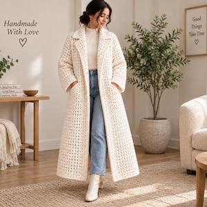 May include: A long, cream-colored crochet coat featuring a notched collar, long sleeves, and two large front pockets. The coat is worn over a white mock-neck top, light blue denim jeans, and white ankle boots. Text reads: Handmade With Love.