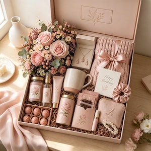 May include: A gift box containing a bouquet of pink roses and daisies, a necklace and earring set, a pink knit blanket with a ribbon, a mug, a candle, a spray bottle, a tube of cream, a tin, tea bags, a scrunchie, a pouch with an A, and a pearl hair clip.