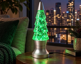 May include: A Christmas tree-shaped lamp with a silver base and top, featuring a clear glass body filled with green liquid and shimmering silver glitter particles that illuminate with a bright green glow when powered on.