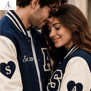 May include: A navy blue and cream varsity jacket featuring a white heart patch with the letter S on the sleeve, a large letter A on the chest, and the text Est. 2006 embroidered in white thread. The jacket has a ribbed collar and snap buttons.