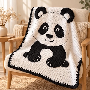 May include: A white and black crochet blanket featuring a large panda bear face and paws design. The blanket has a textured stitch pattern and a thick black border around the edges, showcasing a graphic representation of a panda in high contrast.