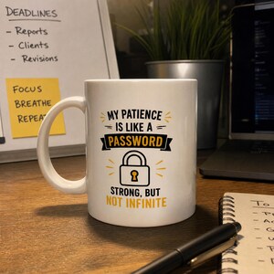 May include: A white ceramic mug featuring black and yellow text that reads: My patience is like a password, strong, but not infinite. The design includes a graphic of a padlock with a yellow keyhole, surrounded by small yellow decorative lines.