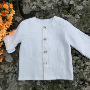 May include: A white linen button-up shirt with a round neckline and five buttons down the front.