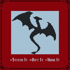 May include: A cross-stitch pattern featuring a black silhouette of a dragon centered on a light blue background. The design is framed by a deep red border with decorative corners and the text "Stitch It • Gift It • Hang It" in white.