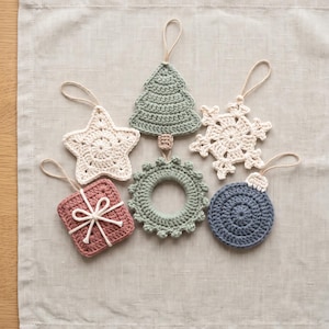 May include: A collection of six crocheted ornaments featuring a star, a Christmas tree, a snowflake, a square gift box with a bow, a circular wreath with small bobbles, and a round bauble, all equipped with thin loops for hanging purposes.