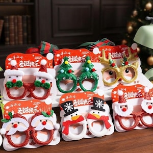 Puede incluir: Una colección de seis gafas festivas con diseños navideños que incluyen a Santa Claus, árboles de Navidad, astas de reno y muñecos de nieve. Cada par está montado sobre un cartón rojo con el texto en chino 圣诞快乐.