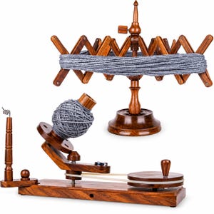 May include: A dark brown wooden yarn swift with a grey yarn skein and a matching wooden yarn ball winder featuring a grey yarn ball. The winder has a horizontal base, a rotating disc with a handle, and a vertical spindle for holding the yarn.