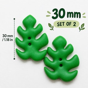 May include: A set of two green leaf-shaped buttons, each featuring two central holes. The buttons measure 30 mm in height. The text 30 mm and SET OF 2 is displayed in green next to the buttons, along with a vertical measurement line indicating 30 mm.