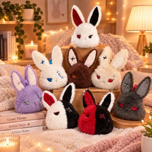 Pode incluir: Uma coleção de oito cabeças de coelho de pelúcia em várias cores, incluindo branco, castanho, roxo, preto e vermelho. Cada brinquedo macio apresenta orelhas compridas, expressões faciais bordadas com olhos em forma de X e textura felpuda.