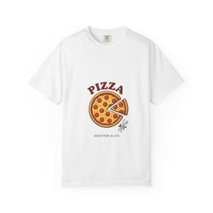 Könnte beinhalten: Ein weißes T-Shirt mit kurzen Ärmeln und einer Grafik einer Peperoni-Pizza, bei der ein Stück abgetrennt ist. Über der Pizza steht das Wort PIZZA in Rot, darunter der Text ANOTHER SLICE. Eine kleine Abbildung von Gabel und Messer ist dabei.
