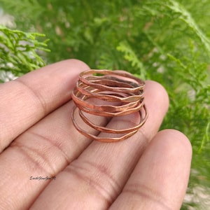 May include: A stack of thin, copper-colored metal rings with a hammered, wavy texture. The rings are circular and have a metallic finish. The text EarthGlowGemTM is visible in the lower left corner of the image.