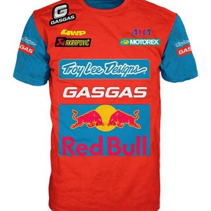 Può includere: Una t-shirt rossa a maniche corte blu con vari loghi di sponsor tra cui GasGas, Troy Lee Designs, Akrapovic, Motorex e Red Bull. La parte anteriore presenta un grande logo Red Bull con due tori rossi che si fronteggiano.