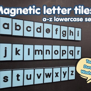 Peut inclure: Un ensemble de tuiles magnétiques avec les lettres minuscules de a à z. Chaque tuile est bleu clair avec une bordure noire et une lettre noire en relief. Le texte "Magnetic letter tiles a-z lowercase set" et "Tactile Durable Washable" est présent.