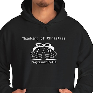 Könnte beinhalten: Ein schwarzer Kapuzenpullover mit einer weißen Grafik von zwei Glocken, die die Binärziffern 1 und 0 tragen. Über den Glocken steht der Text Thinking of Christmas und darunter der Text Programmer Bells in weißer Schrift.