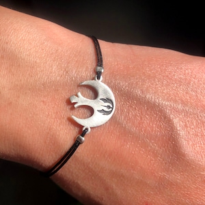 May include: A black string bracelet with a silver Rebel Alliance symbol charm.