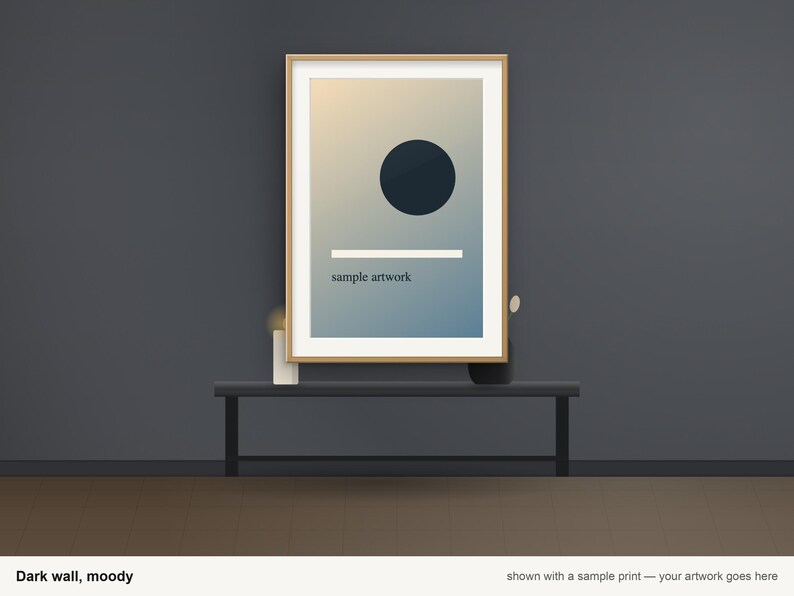 May include: A rectangular wooden frame containing a print with a gradient background, a dark circle, a horizontal white line, and the text "sample artwork" in a small, dark, sans-serif font, centered on a dark gray wall.