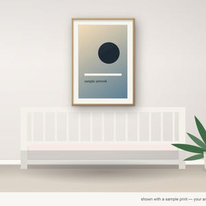 May include: A framed vertical wall print featuring a gradient background transitioning from light beige to blue. The artwork displays a solid dark circle, a horizontal white line, and the text "sample artwork" in small black font.