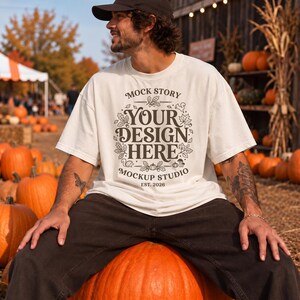 May include: An off-white short-sleeve t-shirt featuring dark brown text that reads MOCK STORY YOUR DESIGN HERE MOCKUP STUDIO EST. 2026, surrounded by a decorative circular frame of autumn leaves, acorns, squirrels, mushrooms, and pumpkins.
