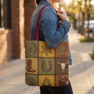Puede incluir: Un bolso tote con asas color granate que presenta un patrón de cuadrícula con nueve ilustraciones de temática western, incluyendo una rueda de carreta, una estrella de sheriff, un cactus, una bota de vaquero, una herradura, un cráneo de buey, una planta rodadora, una fogata y una silla de montar.